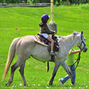 A child being led by an adult on a grey pony.