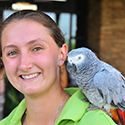 Girl with grey African parrot on her shoulder.