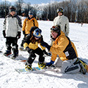 Snowboard instructor assisting a young child in a lesson.