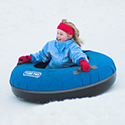 Young girl riding down a hill in a blue snow tube.